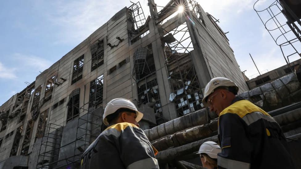 Workers at the site of a damaged power plant, the building has been hit by some kind of air strike