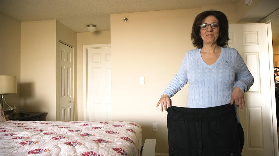 In this Jan 9, 2020 image from video, Anita Saah, 45, holds the size 18-20 pants she used to wear, in her home in Rockville, Md. She had her first weight loss procedure, a sleeve gastrectomy, in July 2018. After experiencing symptoms such as severe dehydration, likely related to her previous acid reflux, she went back for a different weight loss surgery in September 2019. (AP Photo/Federica Narancio)