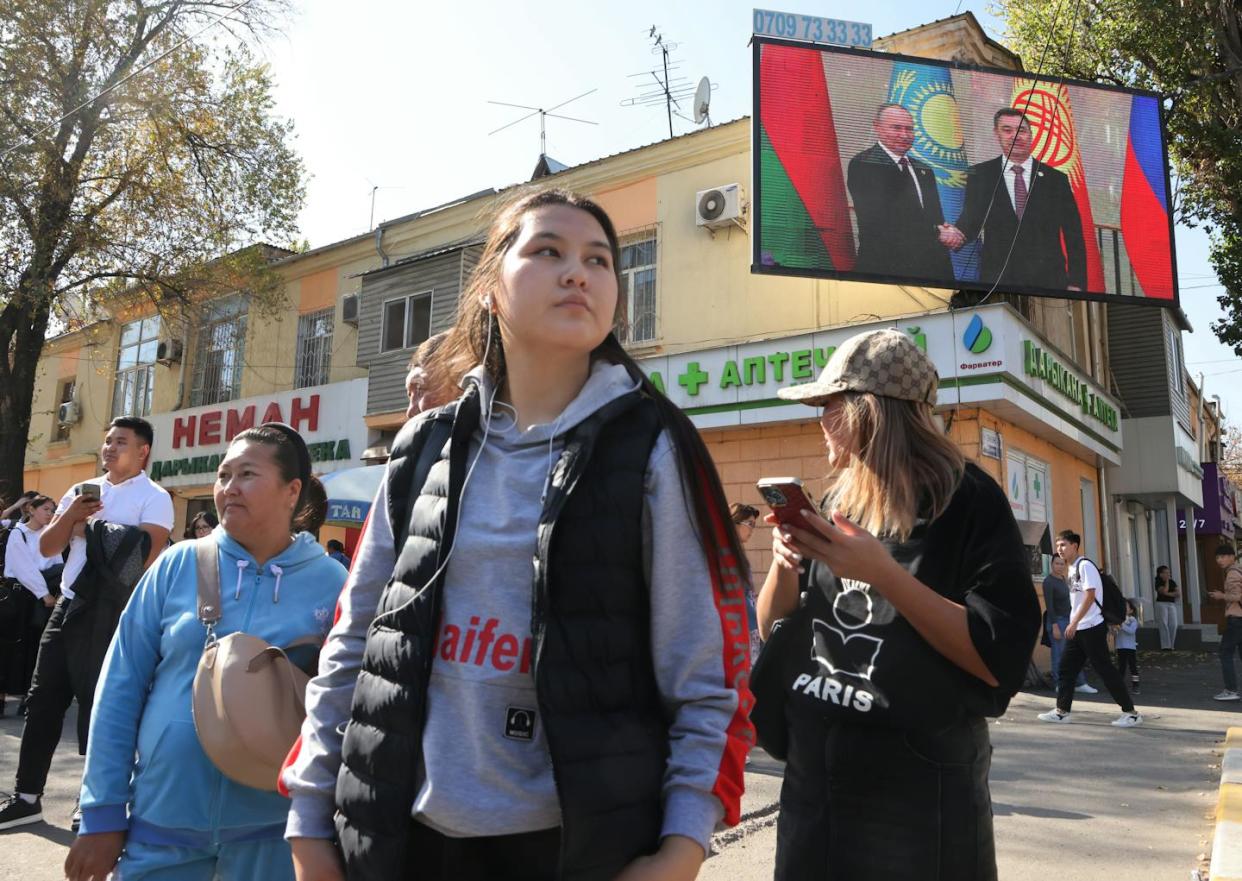 Presidents Vladimir Putin of Russia and Sadyr Japarov of Kyrgyzstan loom over the people of Bishkek. <a href="https://www.gettyimages.com/detail/news-photo/kyrgyz-women-walk-past-to-an-electronic-panel-with-photo-of-news-photo/1719479860?adppopup=true" rel="nofollow noopener" target="_blank" data-ylk="slk:Contributor/Getty Images;elm:context_link;itc:0;sec:content-canvas" class="link ">Contributor/Getty Images</a>