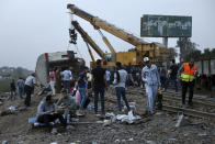 People break their fast during the holy month of Ramadan, at the site of a passenger train that derailed injuring around 100 people, near Banha, Qalyubia province, Egypt, Sunday, April 18, 2021. The train was travelling to the Nile Delta city of Mansoura from the Egyptian capital, the statement said. (AP Photo/Fadel Dawood)