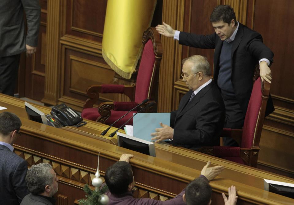 A Ukrainian opposition lawmaker, right back, gestures amid an argument with Ukrainian parliament speaker Volodymyr Rybak, sitting, after a scuffle in the Ukrainian parliament in Kiev, Ukraine, Thursday, Jan. 16, 2014. Lawmakers scuffled in the Ukrainian parliament during a debate on this year's budget. Despite the opposition's efforts to disrupt the vote, the budget draft, which has already been delayed by almost two months, was passed in its second reading. (AP Photo/Sergei Chuzavkov)