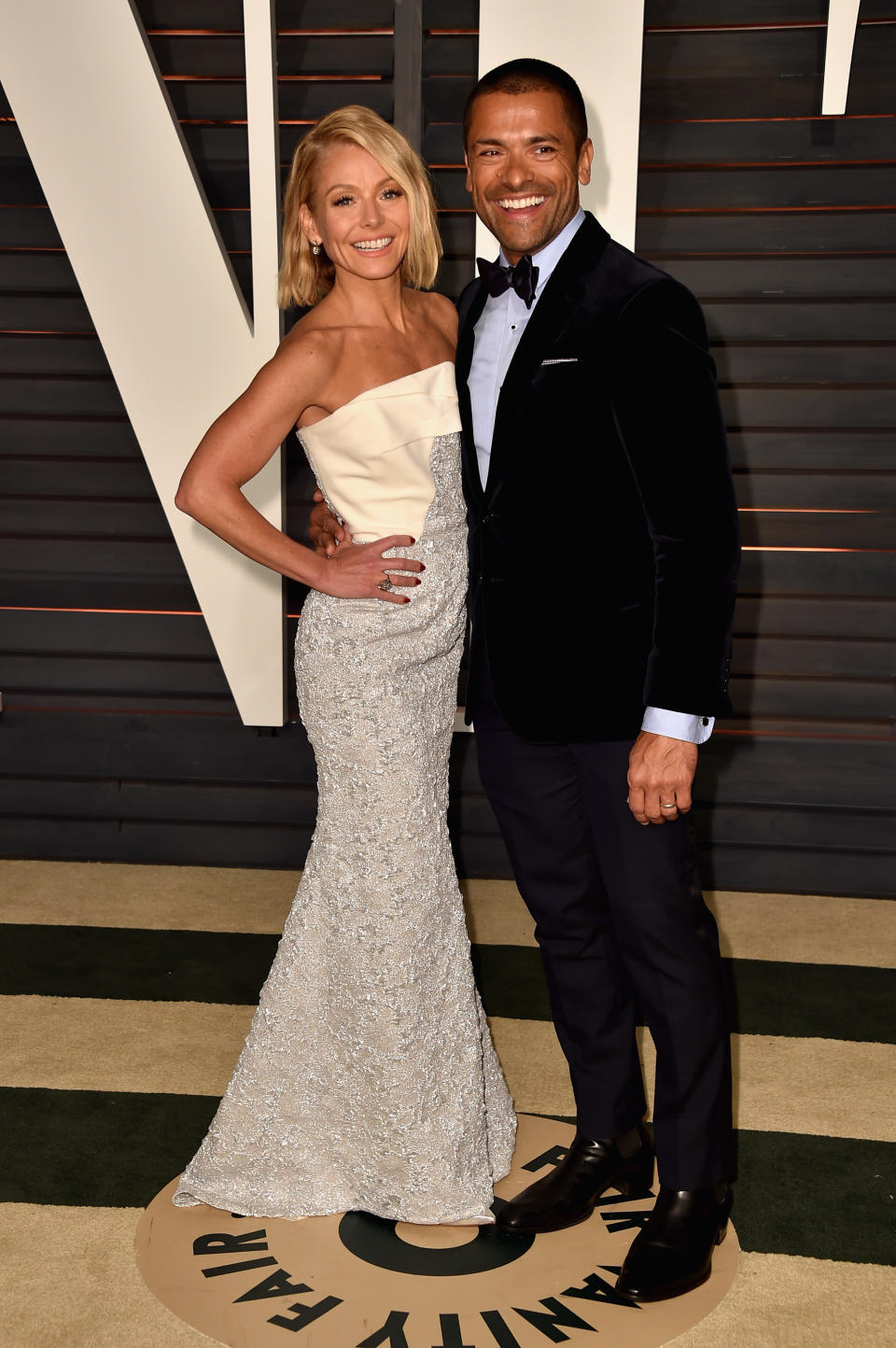 Kelly Ripa wears a white dress next to Mark Consuelos