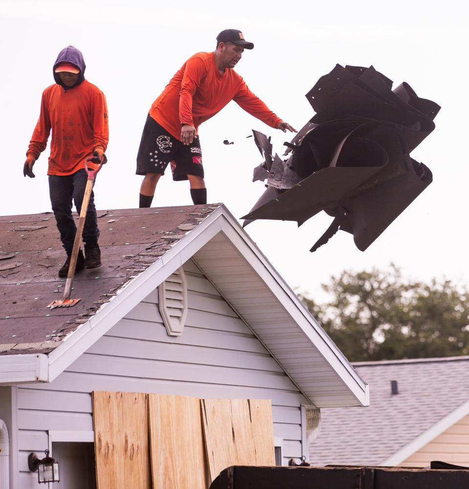 Scott's Roofing employees clear the old roof off Derek Ingram's house on July 26.