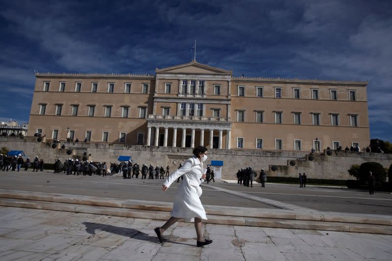 A woman wearing a protective face mask runs in front of the parliament building as Greek university students demonstrate against government plans to set up university police, amid the coronavirus disease (COVID-19) pandemic, in Athens