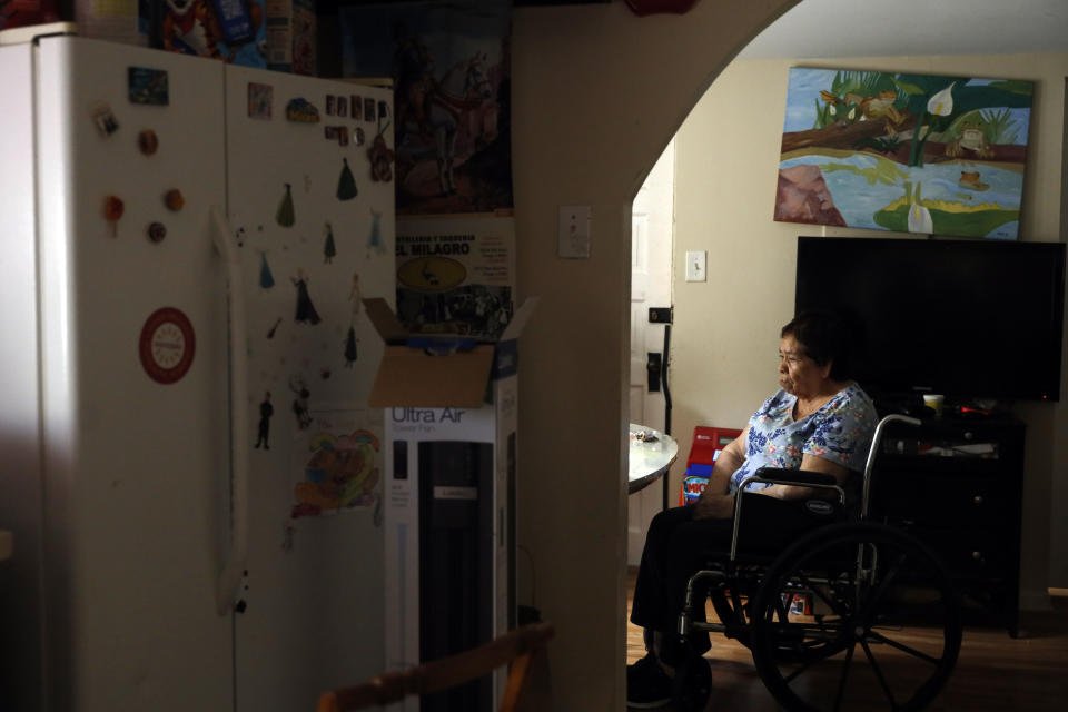 Francisca Perez, 84, sits by the dining table on a wheelchair in her house in Chicago's Little Village neighborhood, Wednesday, June 30, 2021. She suffers from a heart condition, rheumatoid arthritis and depression, among other ailments. Her daughter, Eugenia Rodriguez, hasn't been eligible for insurance coverage after overstaying a visitor visa from Mexico. She used to wake up every two or three hours at night to check on her mother. Since getting health insurance through the Illinois program, her mother has all the medications she needs. (AP Photo/Shafkat Anowar)