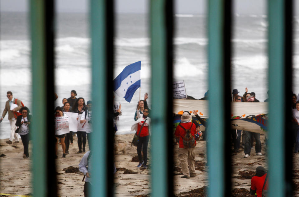 <p>Supporters of a caravan of migrants from Central America wave a Honduran flag while gathering in the United States and near the border fence between Mexico and the U.S. as part of a demonstration prior to preparations for an asylum request in the U.S., as seen through the fence from Tijuana, Mexico April 29, 2018. (Photo: Jorge Duenes/Reuters) </p>