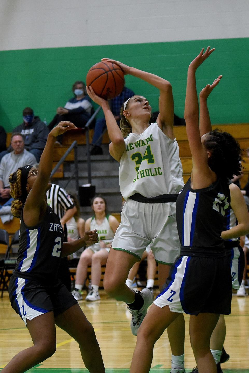 Newark Catholic senior Chloe Peloquin shoots  against Zanesville sophomores Kandrea Sowers (left) and Kylie Osborne (right). The Green Wave defeated the visiting Lady Devils 40-36 on Wednesday, Jan. 26, 2022.