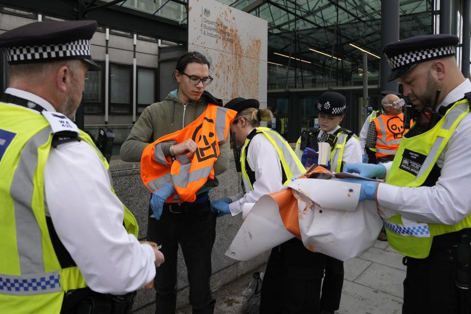 Just Stop Oil protesters throw tomato soup over an outdoor sign at the Department of Business, Energy and Industrial Strategy in London, Oct. 17, 2022. (AP Photo/Alastair Grant)