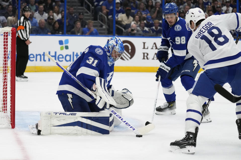 Tampa Bay Lightning goaltender Jonas Johansson (31) makes a save on a shot by Toronto Maple Leafs center Noah Gregor (18) during the first period of an NHL hockey game Saturday, Oct. 21, 2023, in Tampa, Fla. Looking on for the Lightning is defenseman Mikhail Sergachev (98). (AP Photo/Chris O'Meara)