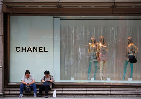 Women sit in front of a Chanel store in Tokyo, Japan May 16, 2018. REUTERS/Issei Kato/Files