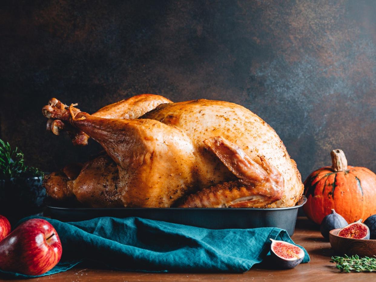 roasted whole turkey on a table with apple, pumpkin and figs for family thanksgiving holiday