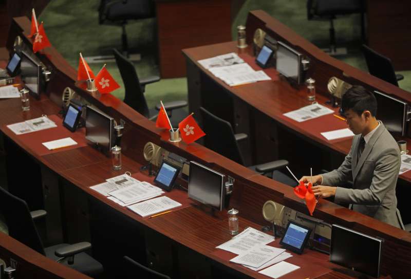 香港立法會議員鄭松泰把建制派議員放在桌上的中國國旗及香港旗幟上下倒轉擺放。（美聯社）