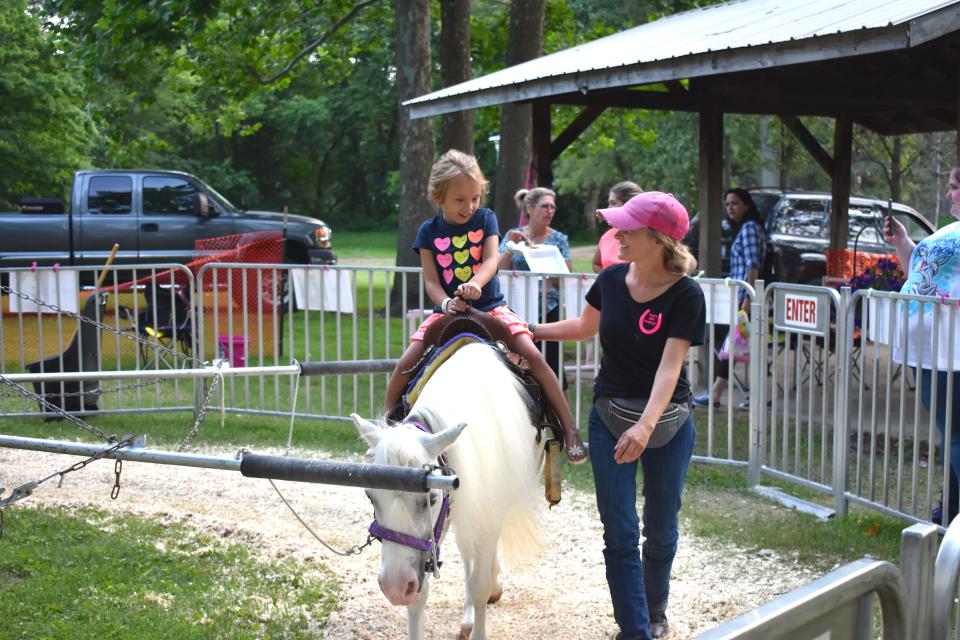 Raelynn Whitman, left, of Whitehouse, Ohio, is assisted on a pony by Paige Neblo of Paige's Pony Parties LLC of Riga July 10, 2021, during Blissfield's River Raisin Festival. Pony rides will be available this weekend at the Kids Corner in Bachmayer Park as part of the 2022 River Raisin Festival, which begins today.