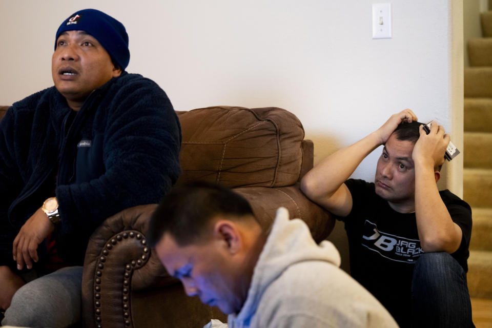 Seafarer Albert Docuyan, right, presses his passport and other documents to his head while Richard Zambales, left, and Reyner Dagalea, center, look on as the group has a call with the Philippine consulate general at a temporary rental house in Lacey, Wash., on Tuesday, Jan. 30, 2024. They are among the two dozen Filipino crew members confined to tuna fishing vessels for months last year without U.S. visas in Westport, Wash. while waiting for backpay from their employer, McAdam's Fish, and recruitment agency Pescadores International. (AP Photo/Lindsey Wasson)