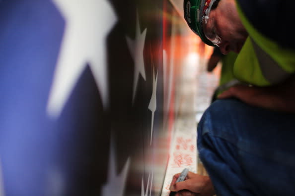 Construction worker Ken Apple signs the last steel beam, along with other members of the crews that helped build the tower, before it is hoisted 977 feet to the top of Four World Trade Center on June 25, 2012 in New York City. The trapezoidal glass and steel office building, which is designed as an architectural backdrop to the September 11 Memorial, is scheduled to open in 2013. (Photo by Spencer Platt/Getty Images)