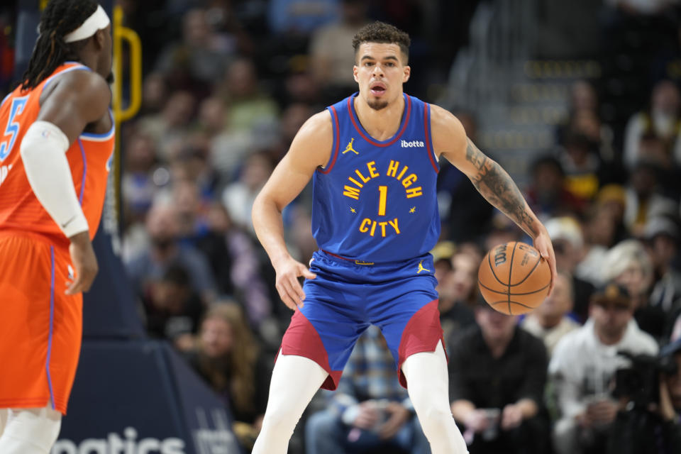 Denver Nuggets forward Michael Porter Jr., right, pulls in the ball as Oklahoma City Thunder guard Luguentz Dort, left, defends in the first half of an NBA basketball game Saturday, Dec. 16, 2023, in Denver. (AP Photo/David Zalubowski)