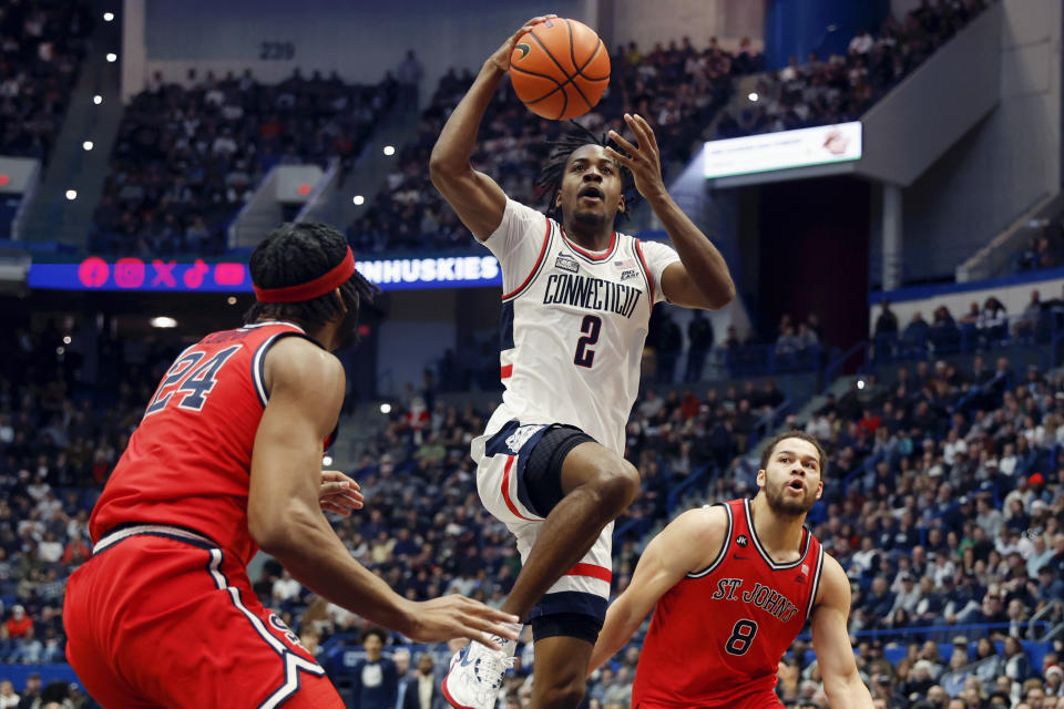 UConn's Tristen Newton (2) shoots against St. John's Zuby Ejiofor (24) and Chris Ledlum (8) during the first half of an NCAA college basketball game, Saturday, Dec. 23, 2023, in Hartford, Conn. (AP Photo/Michael Dwyer)