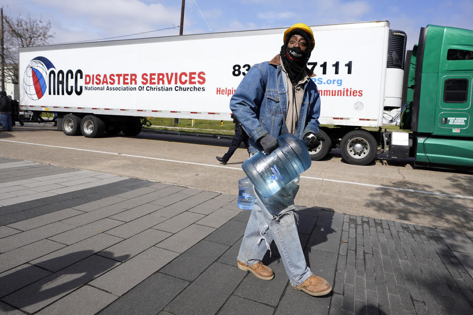 James White carries a bottle of donated water from a distribution site Thursday, Feb. 18, 2021, in Houston. Houston and several surrounding cities are under a boil water notice as many residents are still without running water in their homes. (AP Photo/David J. Phillip)