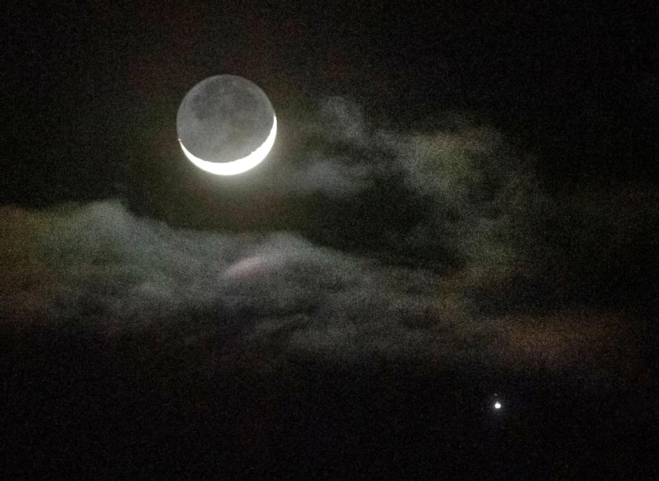 A crescent moon and the planet Jupiter peek through some clouds as seen from Ripon on Wednesday, Feb. 21, 2023.