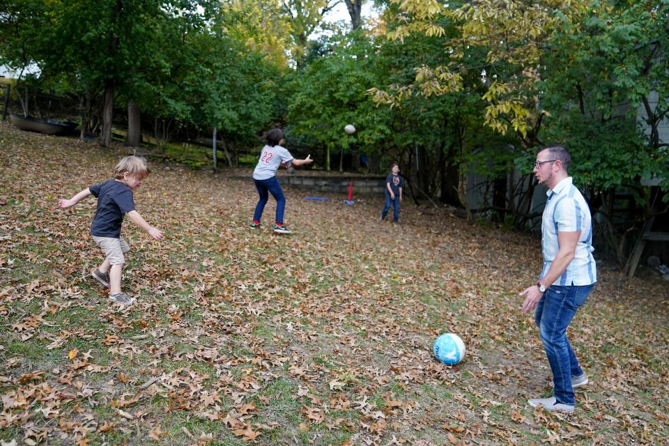 Brandon Long throws the football and kicks the soccer ball around with his sons, Eliah, 11, Mcaiah, 9 and Gideon, 3, in the backyard at their home in Fort Thomas.