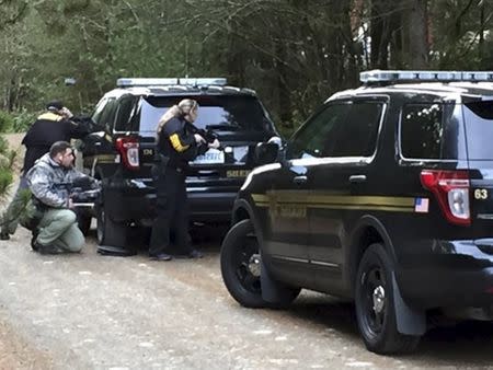 Police officers take cover behind vehicles lining the road during a standoff at a rural property near Belfair, Washington, February 26, 2016 in this handout photo provided by Mason County Sheriff's Office in Shelton, Washington. REUTERS/Mason County Sheriff's Office/Handout via Reuters