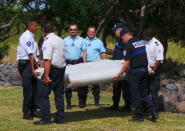 French gendarmes and police carry a large piece of plane debris which was found on the beach in Saint-Andre, on the French Indian Ocean island of La Reunion, July 29, 2015. REUTERS/Zinfos974/Prisca Bigot