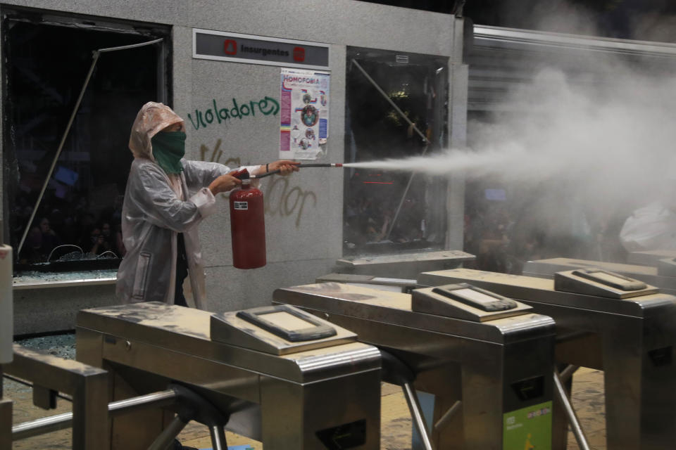 A masked protester aims a fire extinguisher at journalists at a bus station on the sidelines of a women's march sparked by a string of alleged sexual attacks by police officers, in Mexico City, Friday, Aug. 16, 2019. On Friday, hundreds of women demonstrated largely peacefully in downtown Mexico City. But some protesters trashed a nearby bus station. This week, an auxiliary policeman was held for trial on charges he raped a young female employee at a city museum. (AP Photo/Marco Ugarte)