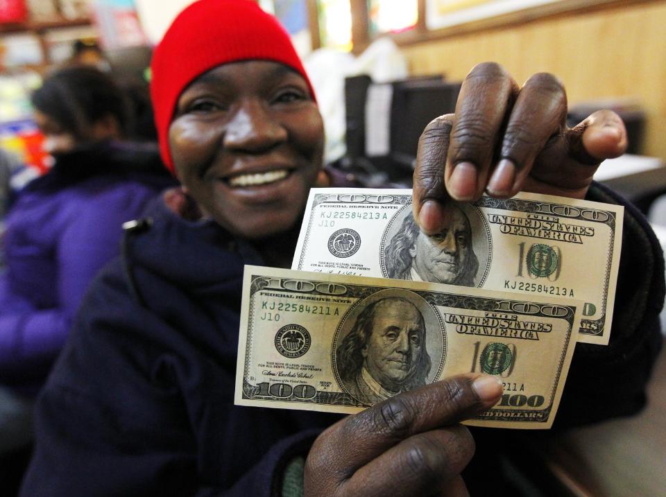 Charlotte Muhammad holds up two $100 dollar bills she got from Secret Santa, at St. Joseph's Social Service Center in Elizabeth, N.J., Thursday, Nov. 29, 2012. The wealthy philanthropist from Kansas City, Mo. known as Secret Santa distributed $100 dollar bills to needy people at St. Joseph's and other locations in Elizabeth. (AP Photo/Rich Schultz)