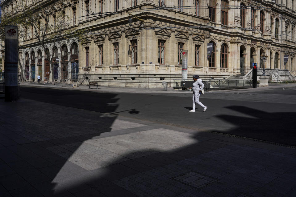 A woman walks through an empty street during a nationwide confinement to prevent the spread of the coronavirus, in the center of Lyon, central France, Sunday, April 5, 2020. The new coronavirus causes mild or moderate symptoms for most people, but for some, especially older adults and people with existing health problems, it can cause more severe illness or death. (AP Photo/Laurent Cipriani)
