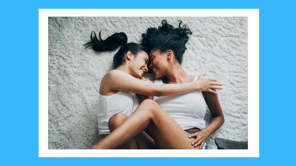  female couple hugging, laughing and touching while on a carpeted floor 