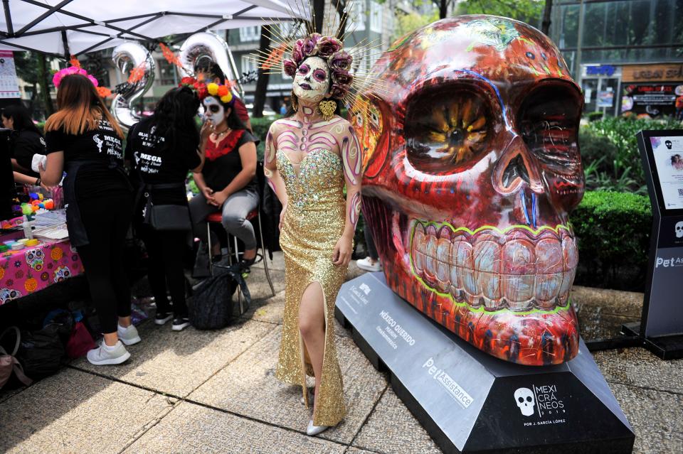 TOPSHOT - A woman fancy dressed as Catrina poses before taking part in the "Catrinas Parade" along Reforma Avenue, in Mexico City on October 26, 2019. - Mexicans get ready to celebrate the Day of the Dead highlighting the character of La Catrina which was created by cartoonist Jose Guadalupe Posada, famous for his drawings of typical local, folkloric scenes, socio-political criticism and for his illustrations of "skeletons" or skulls, including La Catrina. (Photo by CLAUDIO CRUZ / AFP) (Photo by CLAUDIO CRUZ/AFP via Getty Images)