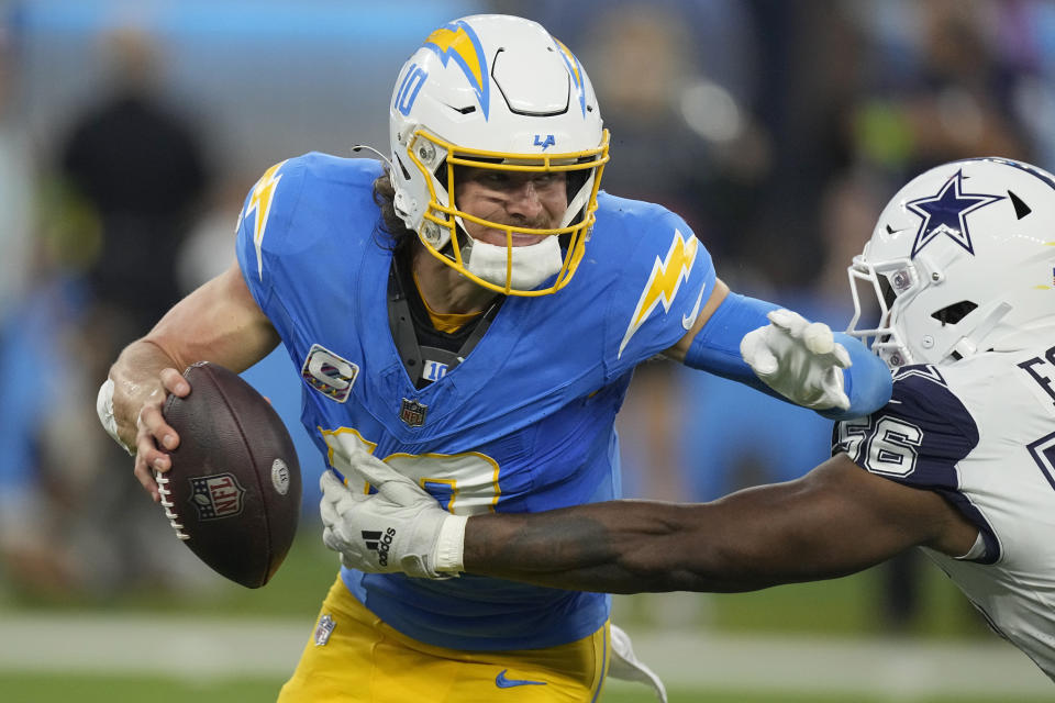 Los Angeles Chargers quarterback Justin Herbert (10) attempts to evade a tackle by Dallas Cowboys defensive end Dante Fowler Jr. (56) during the first half of an NFL football game Monday, Oct. 16, 2023, in Inglewood, Calif. (AP Photo/Mark J. Terrill)