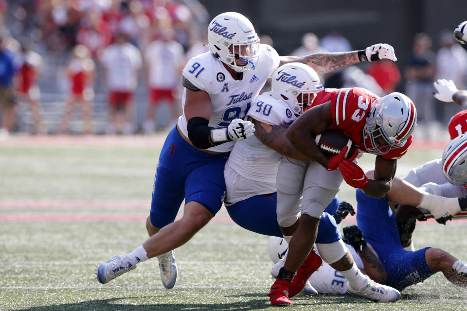 Ohio State running back Master Teague, right, is tackled by Tulsa defensive lineman Cullen Wick, left, and defensive lineman Jaxon Player during the first half of an NCAA college football game Saturday, Sept. 18, 2021, in Columbus, Ohio. (AP Photo/Jay LaPrete)