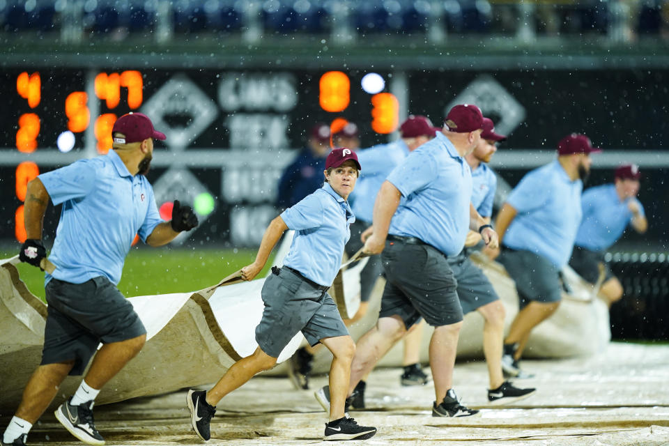 Members of the ground crew pull a tarp over the file during a rain delay in the fifth inning of a baseball game between the Philadelphia Phillies and the Washington Nationals, Thursday, Aug. 4, 2022, in Philadelphia. (AP Photo/Matt Rourke)