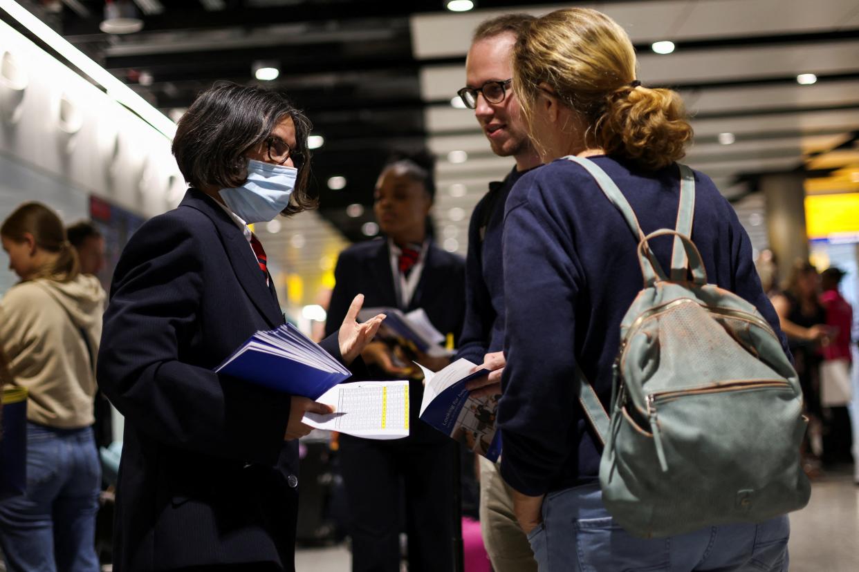 A British Airways staff member speaks to passengers at Heathrow Airport amid air-traffic control outage on Monday 28 August (Reuters)