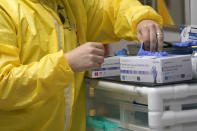 FILE - In this July 6, 2020, file photo, a medical student reaches for some gloves while working inside the Coronavirus Unit in a Houston hospital. Hospital data related to the coronavirus pandemic in the U.S. will now be collected by a private technology firm, rather than the Centers for Disease Control and Prevention — a move the Trump administration says will speed up reporting but one that concerns some public health leaders. (AP Photo/David J. Phillip, File)