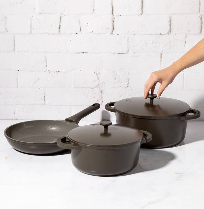 Goodful Charcoal Cookware with a hand pulling off the lid.