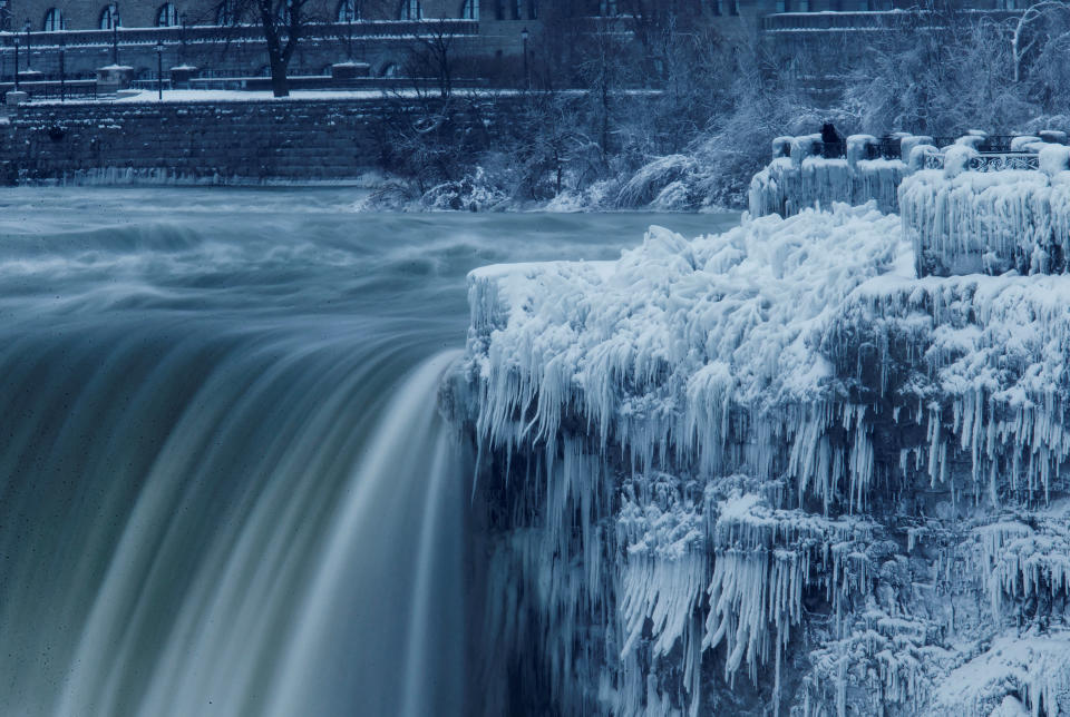 A lone visitor takes a picture near the brink of the ice covered Horseshoe Falls in Niagara Falls, Ontario, Canada, Jan. 3, 2018.