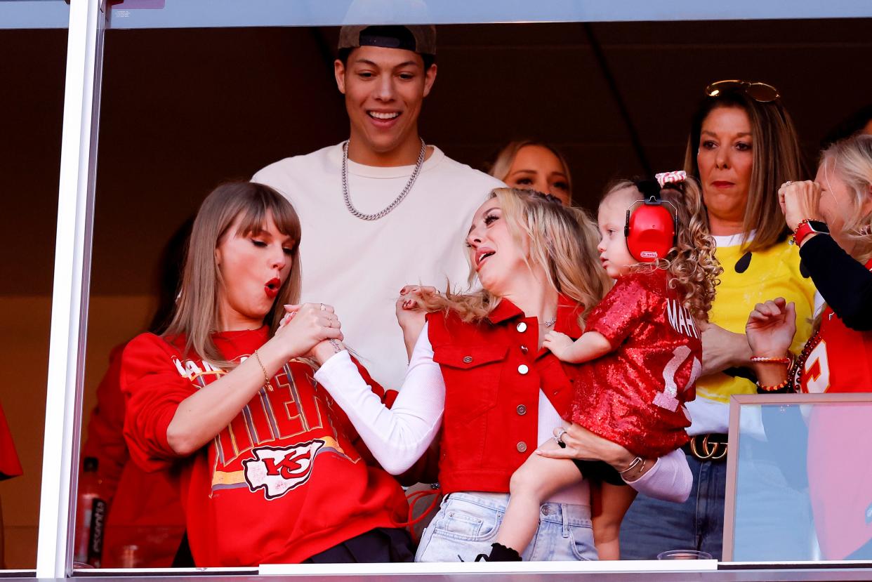 Taylor Swift and Brittany Mahomes wear red Chiefs gear and celebrate a touchdown in the VIP box at Arrowhead Stadium.