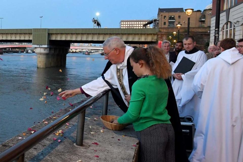 Tribute: petals are scattered onto the water by the Bishop of Southwark at the service (PA)