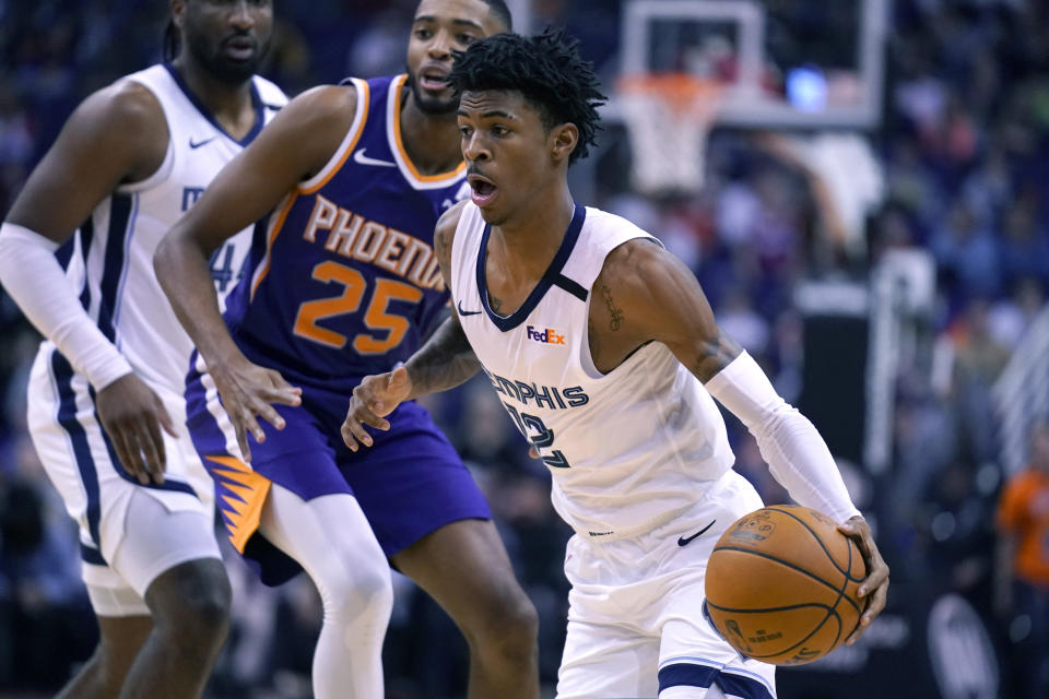 Memphis Grizzlies guard Ja Morant (12) drives past Phoenix Suns forward Mikal Bridges in the first half during an NBA basketball game, Sunday, Jan. 5, 2020, in Phoenix. (AP Photo/Rick Scuteri)