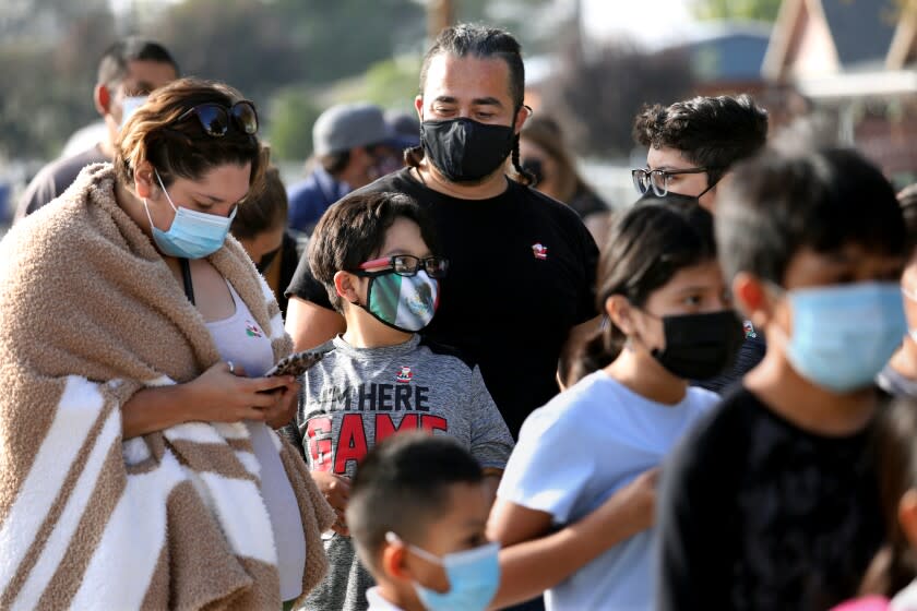 DELANO, CA - NOVEMBER 17: Monique and Sergio Millan, of Delano, wait in line with children Sebastian Millan, 8, and Sergio Millan, 12, to receive the Pfizer-BioNTech COVID-19 vaccine administered by the Delano Union School District Student Support Services in partnership with the California Farmworkers Foundation in the Central Valley on Wednesday, Nov. 17, 2021 in Delano, CA. (Gary Coronado / Los Angeles Times)