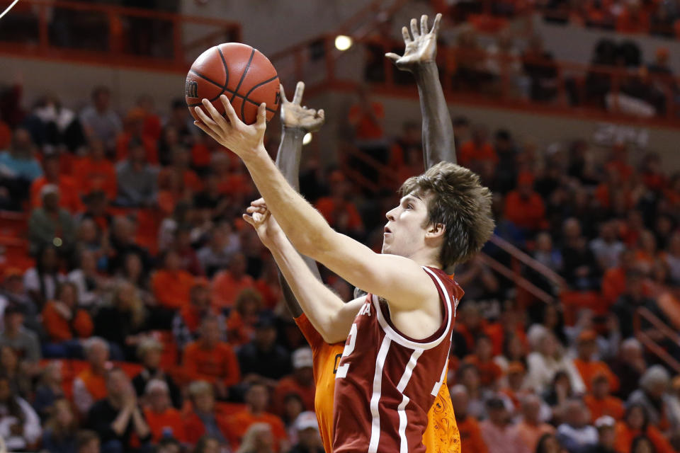 Oklahoma guard Austin Reaves, front, shoots in front of Oklahoma State forward Yor Anei, rear, in the second half of an NCAA college basketball game in Stillwater, Okla., Saturday, Feb. 22, 2020. (AP Photo/Sue Ogrocki)