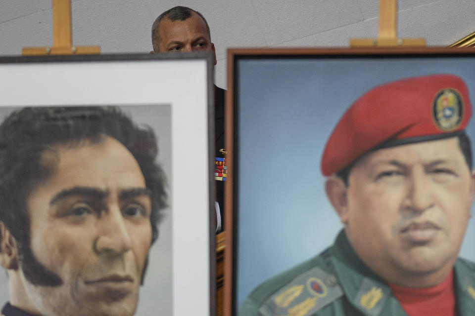 Un militar venezolano se sienta tras imágenes del expresidente Hugo Chávez, a la derecha, y el héroe de la independencia Simón Bolívar, durante el discurso anual sobre el estado de la nación del presidente de Venezuela, Nicolás Maduro, en la cámara de la Asamblea Nacional Constituyente en Caracas, Venezuela, el martes 14 de enero de 2020. (AP Foto/Matias Delacroix)