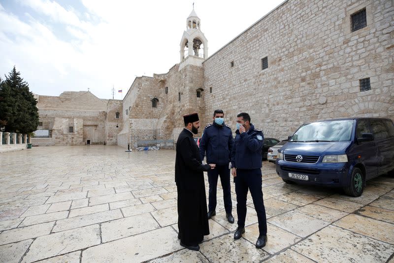 Palestinian police officers stand guard outside the Church of the Nativity that was closed as a preventive measure against the coronavirus in Bethlehem in the Israeli-occupied West Bank