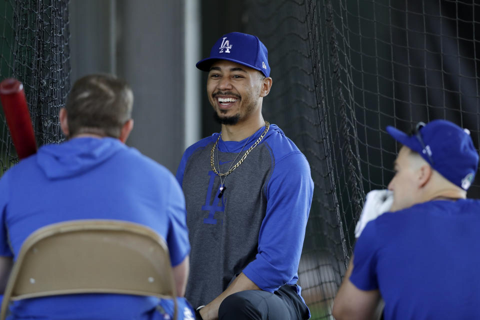 Los Angeles Dodgers outfielder Mookie Betts, center, talks with second baseman Max Muncy, left, and right fielder Joc Pederson, right, during spring training baseball Monday, Feb. 17, 2020, in Phoenix. (AP Photo/Gregory Bull)