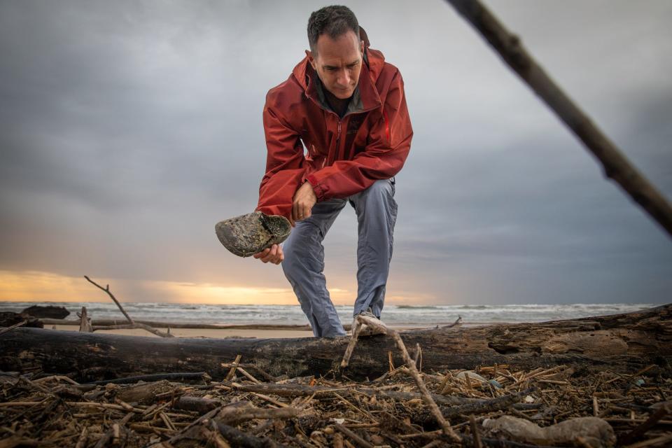 Jace Tunnell, a marine biologist and community engagement director with Harte Research Institute, picks up a shoe while looking through a pile of debris and driftwood at Padre Island National Seashore on Tuesday, March 19, 2024, in Corpus Christi, Texas.