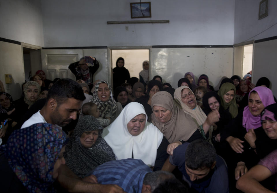 Relatives of Hamas security forces member, Mahmoud al-Adham, 28, mourn over his body during his funeral inside his home, in the town of Jabaliya, northern Gaza Strip, Thursday, July 11, 2019. Hamas' armed wing said Thursday that Israeli the army "deliberately" fired at al-Adham, in the northern town of Beit Hanoun. The Israeli military said it noticed two "armed suspects" near the Gaza-Israel perimeter fence and responded with warning shots. (AP Photo/Khalil Hamra)