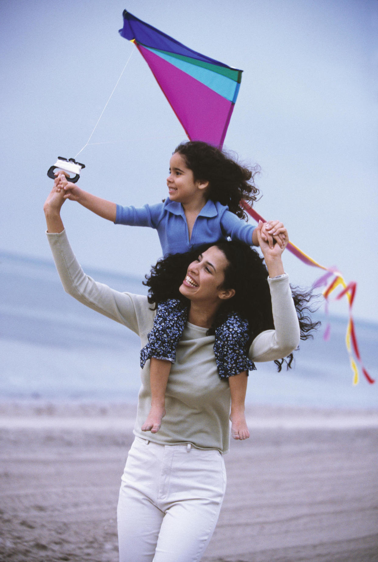mother and daughter flying at kite at beach (Ariel Skelley / Getty Images)