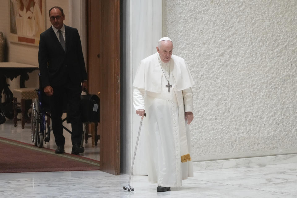 Massimiliano Strappetti, left, watches Pope Francis walking in thew Paul VI hall on the occasion of the weekly general audience at the Vatican, Wednesday, Aug. 3, 2022. Francis has promoted the Vatican nurse whom he credited with saving his life to be his "personal health care assistant." The Vatican announced the appointment of Massimiliano Strappetti, currently the nursing coordinator of the Vatican's health department, in a one-line statement Thursday.(AP Photo/Gregorio Borgia)
